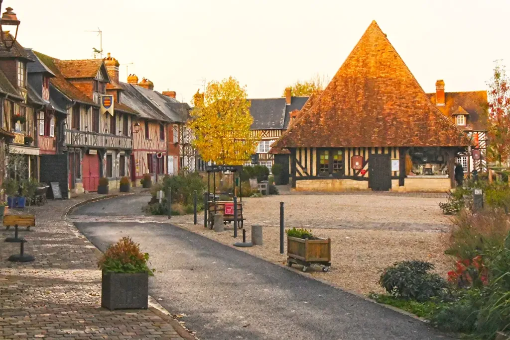 Place du centre de Beuvron-en-Auge avec maisons à colombages et halles à droite, village du Pays d’Auge en Normandie