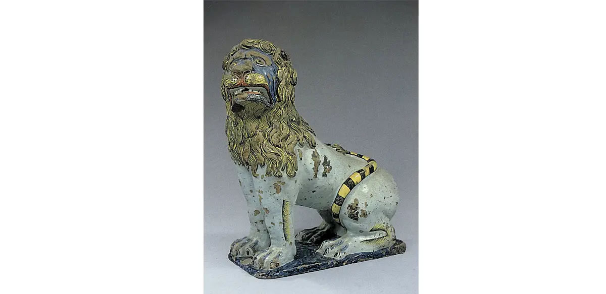 Photo d'un grand lion assis, en faïence de Rouen à décor polychrome daté du XVIIe siècle.