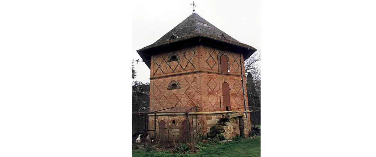 Saint-Christophe-le-Jajolet, Ferme du château de Sassy – Ce colombier original construit dans la seconde moitié du XIXe siècle se distingue des autres par un plan de construction hexagonal et un parement de briques à décor losangé. On remarquera les petites portes basses du rez-de-chaussée enfermant le poulailler. (Photo Jeannine Rouch © Patrimoine Normand)