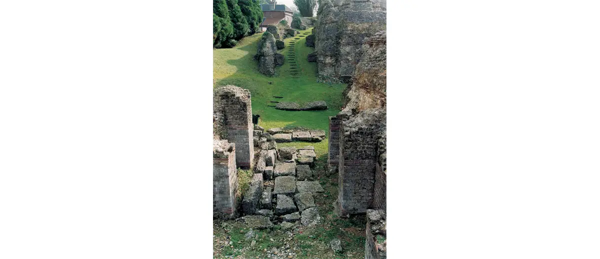 Voici une vue intéressante sur le couloir permettant d’accéder au second maenianum. Au premier plan, la partie nord du côté de la scène avec les restes d’un dallage. Au centre de la photo, le « vide » donne sur le vomitoire est. Au fond, le couloir monte à l’étage supérieur de la cavea en suivant la pente naturelle de la colline.