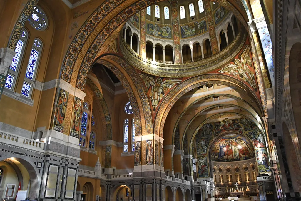 L'intérieur de la basilique Sainte-Thérèse illustre toute la richesse de son architecture néo-byzantine, sublimée par d'imposantes mosaïques qui comptent parmi les plus vastes ensembles décoratifs religieux du XXᵉ siècle.